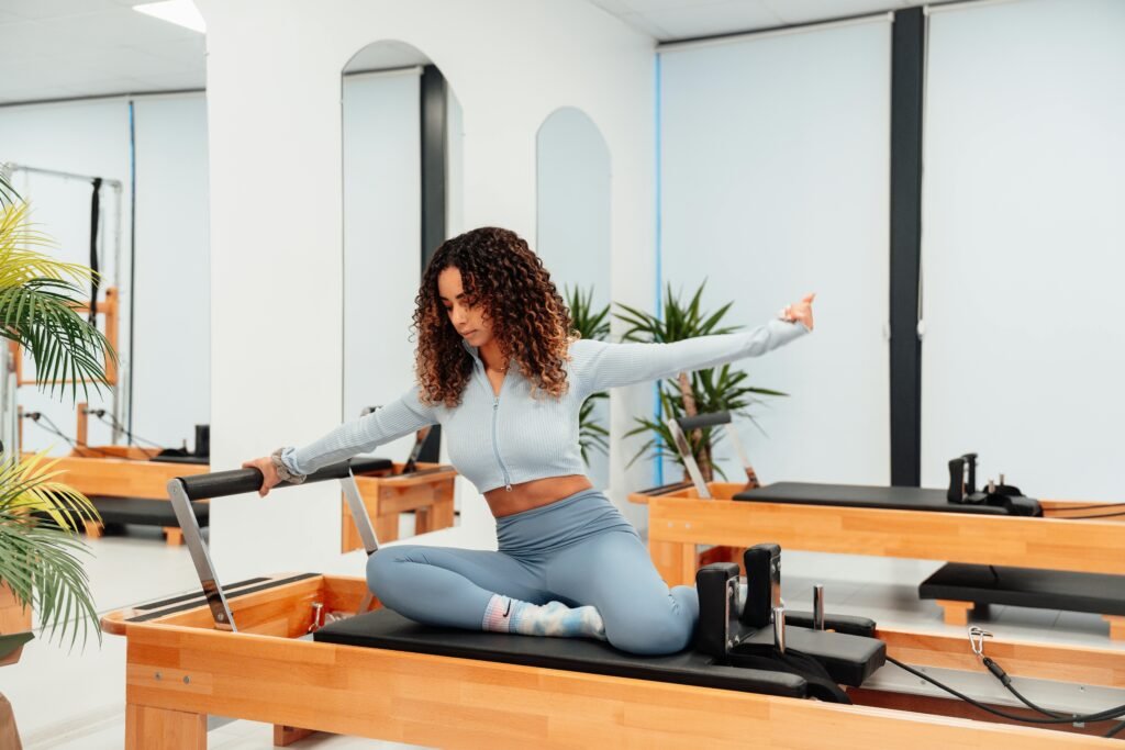 A woman exercising on a reformer in a pilates studio, embodying a healthy lifestyle.